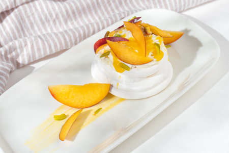 Dessert Pavlova of meringue with passion fruit, nectarines and pistachio on white background for restaurant menu.の写真素材