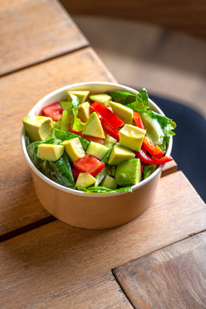 Avocado and fresh tomatoes salad in bowl, top view. Concept Food For Parties. fast food. Healthy lunch. Food delivery in disposable plate of craft paper. Eco-friendly cardboard packaging environment protectionの写真素材