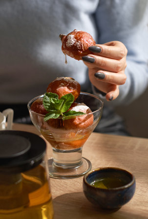 Bowl of Lokma Turkish, loukoumades Greek with other names in other languages, female hands and pastries deep fried dough.の写真素材