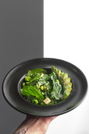 Health food. Fresh green salad on a black plate. Healthy lunch vegetarian. Restaurant vegan food.の写真素材