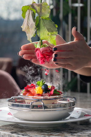 Ice cream dessert with berries and rose petals frozen in nitrogen. Dessert recipe concept serving in the restaurant hall.の写真素材