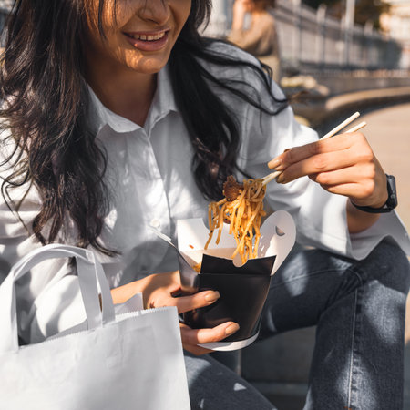 Young woman eating Wok Noodles asian food using choopsticks from take away deliveryの写真素材