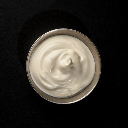 Mayonnaise sauce in a metal gravy boat on a black background for fast food, top viewの写真素材