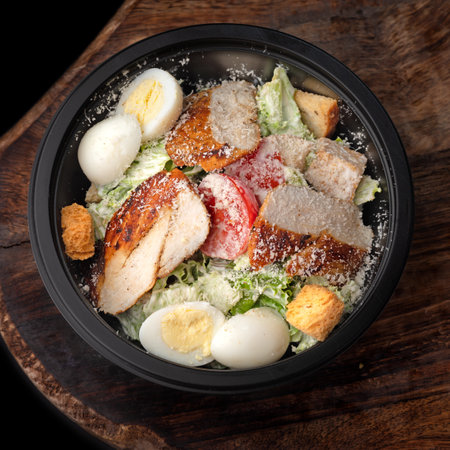 Caesar salad. To Go Salad in round black lunchbox, dish on a tray, copy space, food for menu and advertising. close upの写真素材