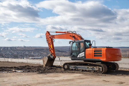 Large orange crawler excavator against backdrop of sky and an overcast dramatic summer sky