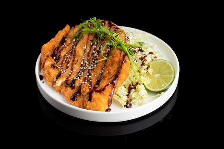 German schnitzel with cabbage salat and sauce on black plate.の写真素材