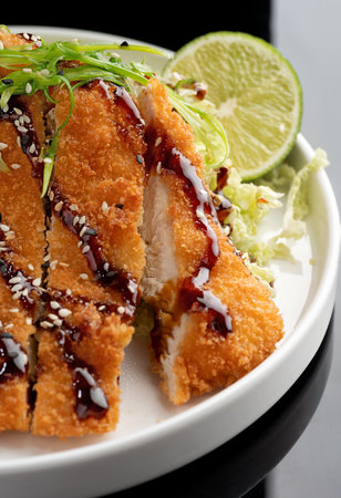 German schnitzel with cabbage salat and sauce on black plate.の写真素材
