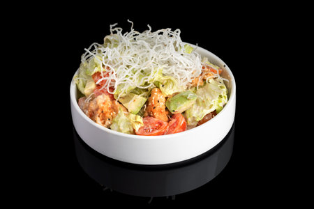 Puff salad with shrimp, avocado and tomato, seasoned with yogurt sauce on plate. restaurant dish on a black background with reflection. menu restaurant.の写真素材