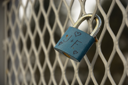 Detail of padlock locked on mesh. Heart and J+F wroten on padlockの写真素材