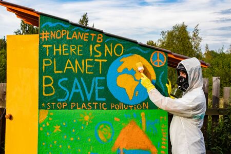 A man in a gas mask and a chemical protection suit paints the concept of the environment. There is no planet B. Save the planet earth. Stop plastic pollution.の写真素材