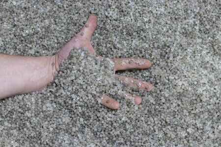 Hand on a background of recycled plastic granules. Granules are used to produce plastic stretch film and bagsの写真素材