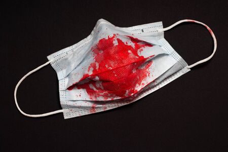 The medical mask is stained with red blood. The concept of fear of panic before coronavirus COVID-19の写真素材