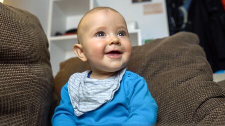 A close up of an adorable baby boy playing and smiling into the camera.