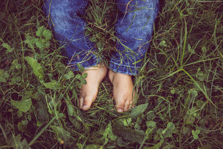 Small baby legs with jeans on and no socks on a grass.