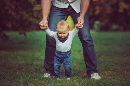 A cute baby boy and his attractive fahter learning to walk in nature.の写真素材