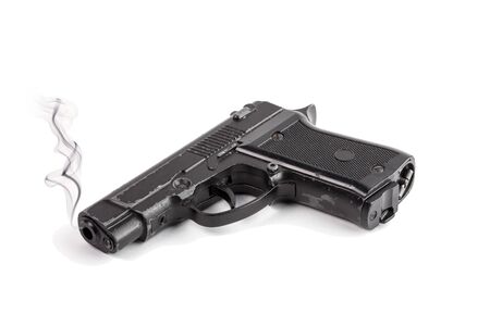 Black steel pistol with traces of use and smoke coming out of the barrelの写真素材