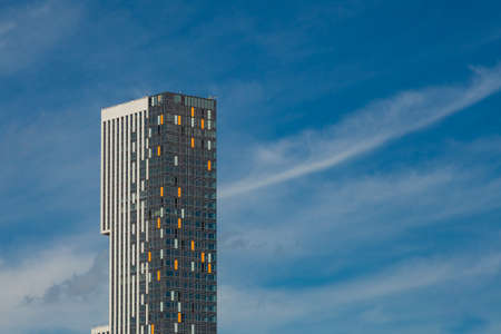 Modern building made of glass and concrete with colored inserts on a background of blue sky