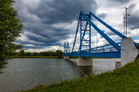 Picturesque blue footbridge across the riverの写真素材