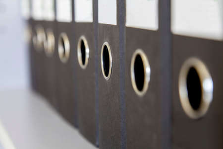 A number of office folders standing on the shelf of the cabinetの写真素材