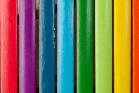 Wooden planks painted in rainbow colors, arranged in a row on a white isolated background