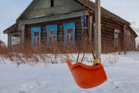 Old homemade children's swing on the background of a wooden village house
