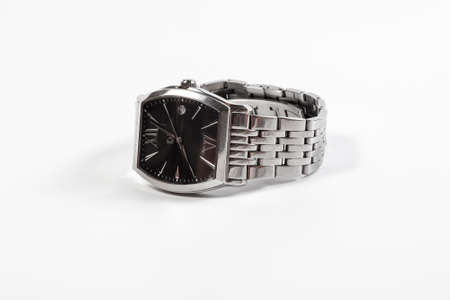 Silver men's wrist watch with a black dial lies on a white background