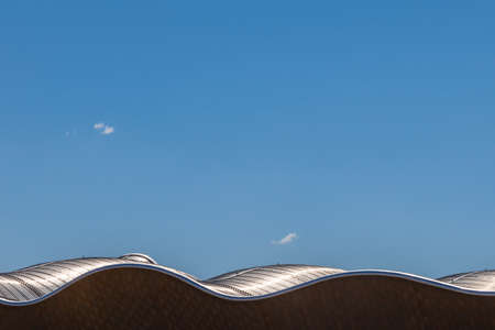 Wavy futuristic building roof against blue sky background.