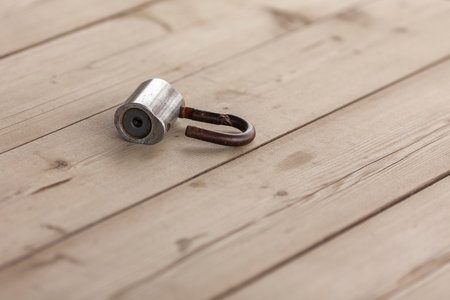 An old padlock lies on a wooden table.の写真素材