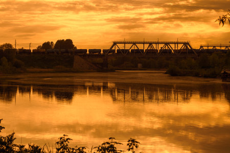 Freight Train Carrying Oil Products Crossing Railway Bridge at Sunset.の写真素材