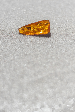 amber shiny with inclusions on sandの写真素材