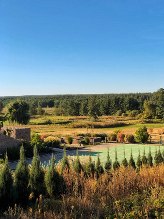 A view of a countryside landscape with a tennis court and surrounding greenery under a blue sky.の写真素材