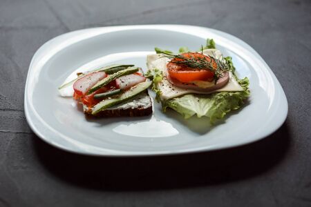 Two delicious sandwiches on the white plate. Grey textured background. Breakfast time.の写真素材