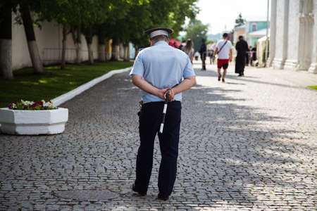 tired police officer is patrolling the street of the historical part of the city. Kolomna, Moscow region/Russia - 06.06.2020.のeditorial素材