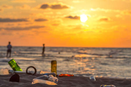 Plastic bottles and trash on the beach at sunset. Environmental pollution concept.の写真素材