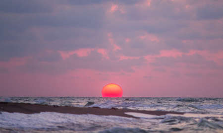 Beautiful sunset on the beach. The sun sets over the sea.の写真素材