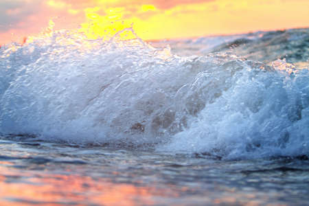 Splashing waves on the beach at sunset. Beautiful natural background.の写真素材