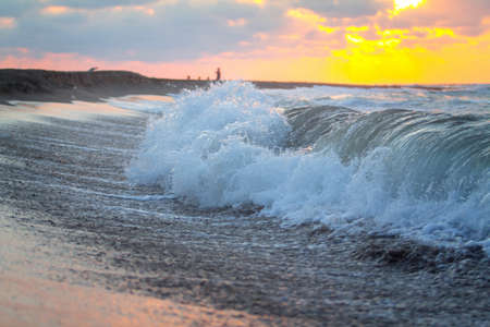Waves breaking on the beach at sunset. Beautiful natural background.の写真素材
