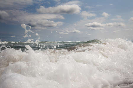 Sea waves. Sea foam. Blue sky with white clouds.の写真素材