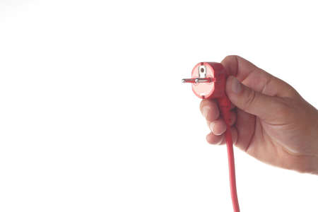 Woman's hand holding a red power plug isolated on white background.