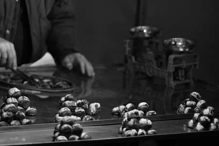 Black and white photo of a street vendor selling chestnuts on a street stallの写真素材