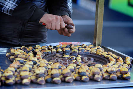 Close-up of a street vendor selling roasted chestnuts on the streetの写真素材