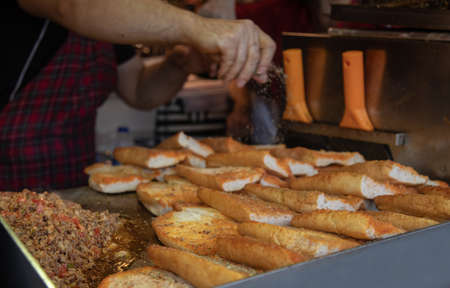 Close-up of the hands of a street vendor who pours the cheese to the bread.の写真素材