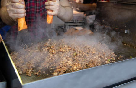 Close-up of a man in a checkered shirt is preparing meat and vegetables.の写真素材