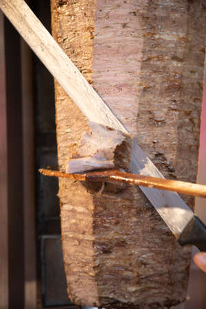 Cutting meat with a knife on a skewer. Close-up.の写真素材