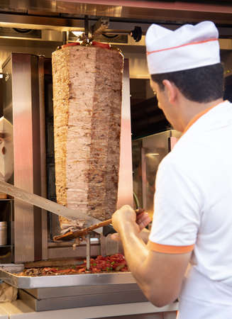 A man in a white T-shirt and a blue cap is cooking in a restaurant.の写真素材