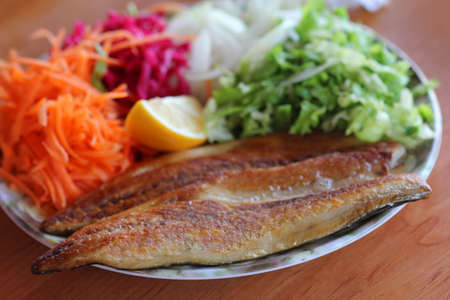 Fried fish with salad and lemon on wooden table, Thailand.の写真素材