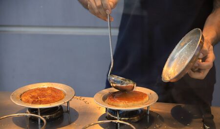 Pouring syrup on a traditional Turkish dessert (Kunefe)