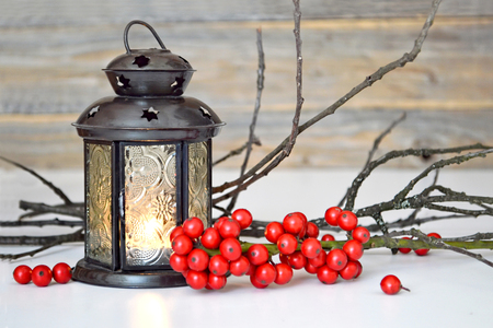 Christmas greeting card with lantern, twigs and red berries on itの写真素材