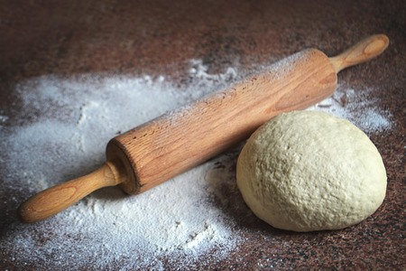 Homemade dough and rolling pin on kitchen boardの写真素材