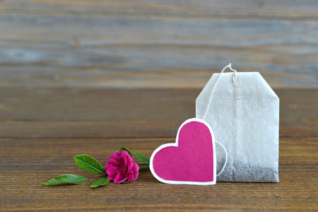 Tea bag with heart-shaped tag and roseの写真素材